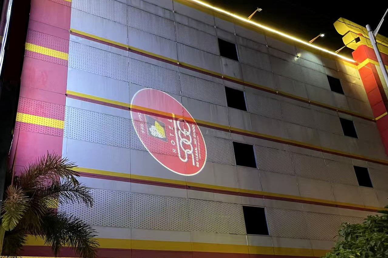 Circular logo projected onto a multistory building facade at night.