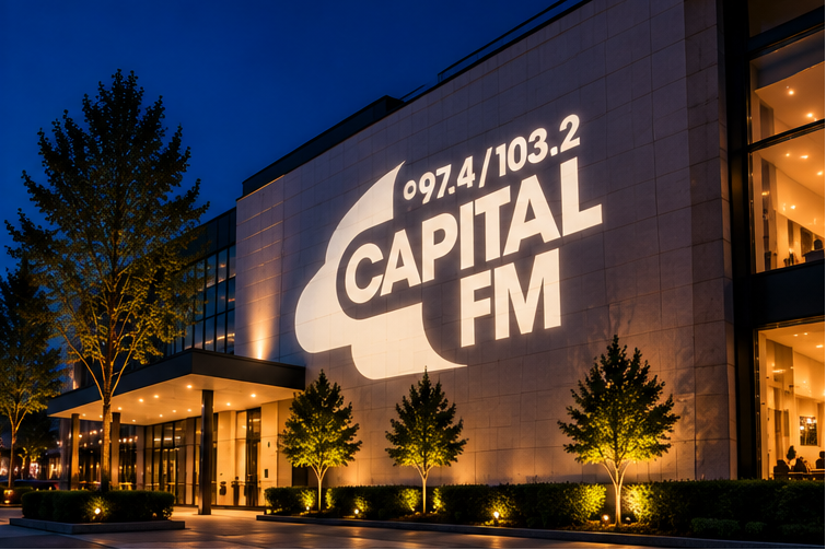 Capital FM radio station building exterior at dusk, with large illuminated white logo text reading '97.4/103.